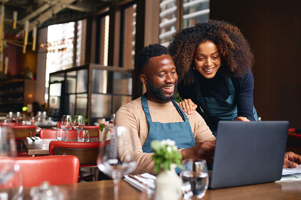 Small business owners using laptop in restaurant.