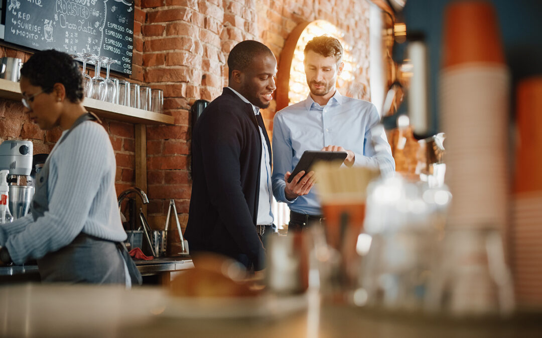 Two people discuss the display of a tablet in a restaurant setting